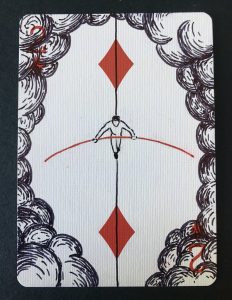 A playing card decorated with a drawing of a man walking across a tightrope among clouds.